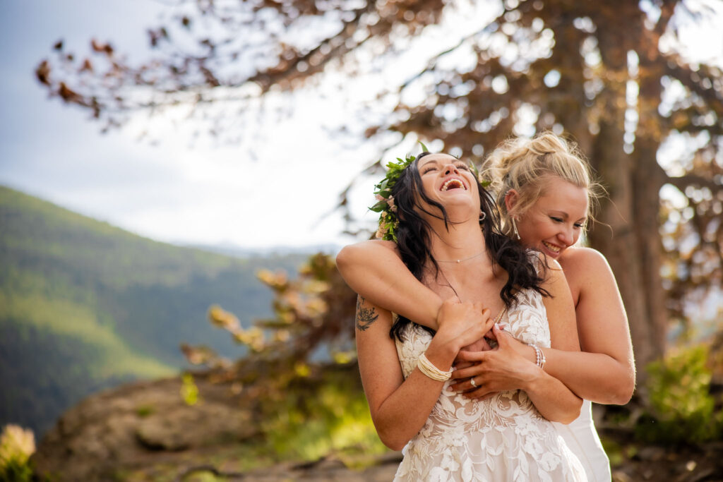 LGBTQ elopement in the Colorado mountains with two brides sharing a candid, joyful moment outdoors.