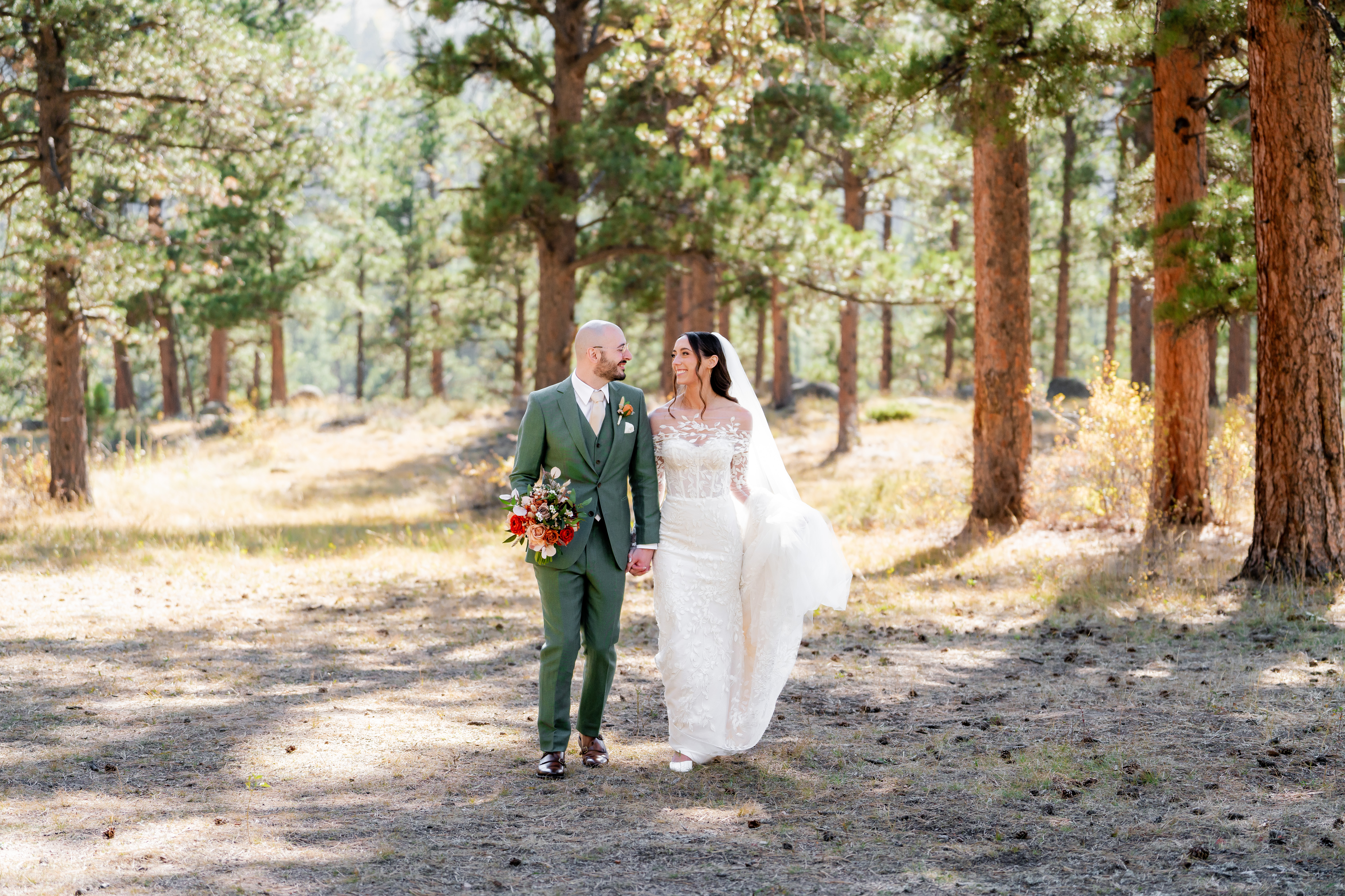 Bride and groom walking hand in hand through a forest during an intimate Colorado elopement with fall colors