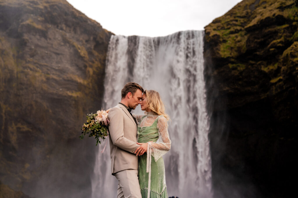 Bride and groom romantically embracing each other at Skógafoss in Iceland during their elopement.