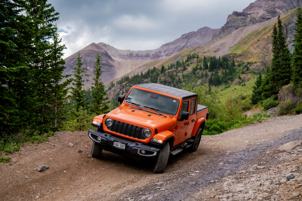 Orange Jeep navigating the scenic mountain roads through Yankee Boy Basin in Colorado's San Juan Mountains.