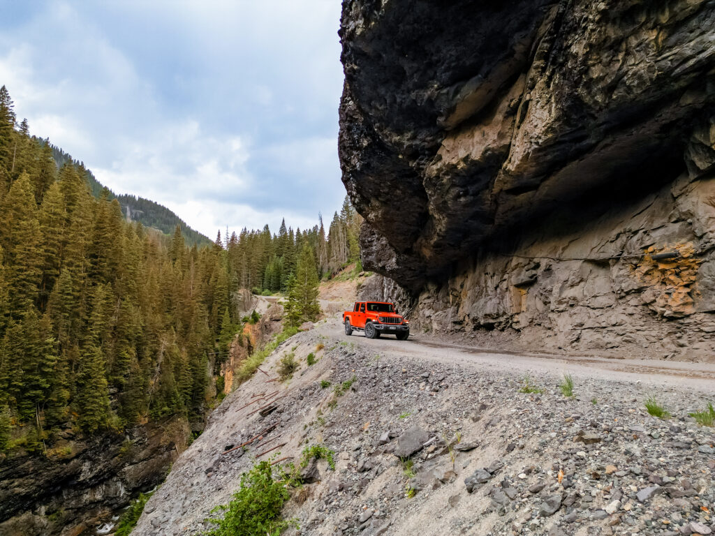 A Jeep drives beneath the famous rock overhang along the Yankee Boy Basin 4x4 road outside Ouray, Colorado.