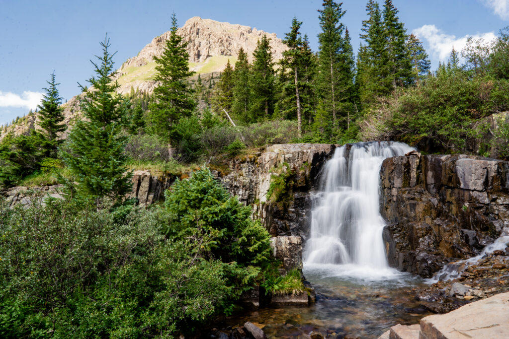 Beautiful waterfall surrounded by pine trees and rocky cliffs in Yankee Boy Basin near Ouray, Colorado.